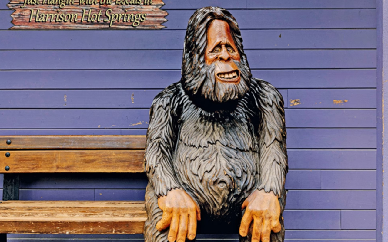 a statue of sasquatch on a bench in harrison hot springs